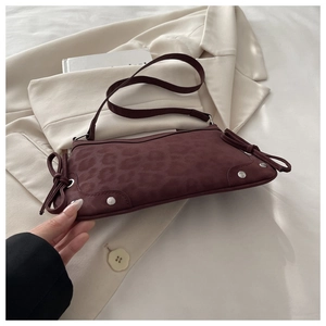 Detail of burgundy leopard embossed shoulder bag with bow ties and silver studs