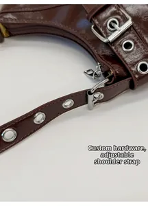 Detail of dark brown glossy leather with custom hardware and adjustable strap