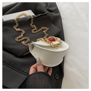 Detail of white semi-circular crossbody bag with red strawberry decor and gold chain