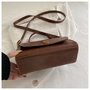Close-up of vintage brown PU leather handbag featuring a bronze twist lock and top handle