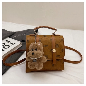 Detail of vintage brown leather handbag with owl print and plush bear charm accessory