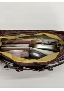 Detail view of burgundy leather baguette bag showing spacious yellow lining and essentials