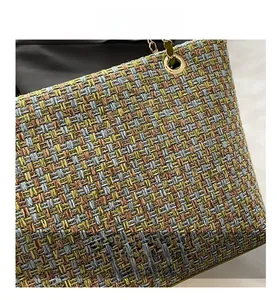 Macro shot of colorful tweed woven texture with green leather trim and gold metal rings