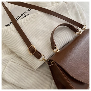 Detail of a dark brown vintage crossbody bag with gold hardware and fine stitching