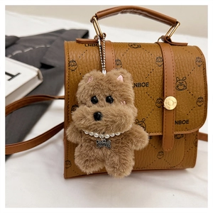 Detail of vintage brown leather bag featuring LNBOE text and a plush bear charm accessory