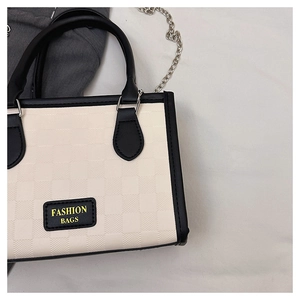 Close-up of checkerboard tote bag with black leather trim and silver metal chain strap