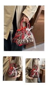 Dettaglio borsa leopardata con manico rosso, fiocco in pizzo e ciondolo a forma di ciliegia