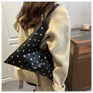 Detail view of black rivet underarm bag with gold studs on matte leather shoulder strap