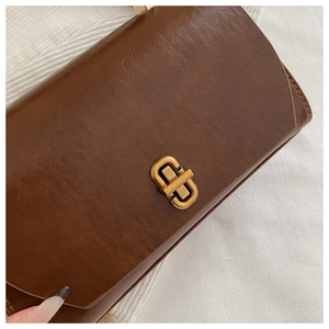 Close-up of vintage golden metal twist lock on a brown glossy leather shoulder bag