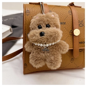 Detail of plush dog keychain with pearl necklace on a vintage monogram brown backpack