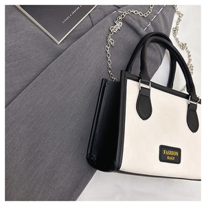 Detail of minimalist black and white textured leather tote bag with silver chain strap