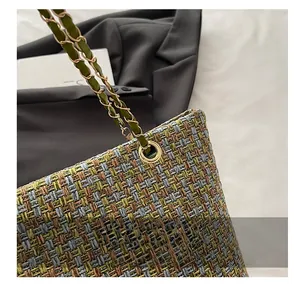 Detailed macro view of woven tweed tote fabric with luxury gold chain and leather strap