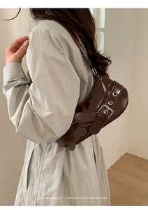 Detail view of a retro dark brown glossy baguette bag with silver buckle and bear charm