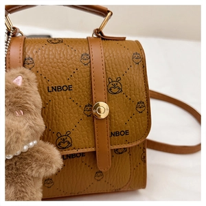 Detail of vintage brown pebble grain faux leather bag with cartoon prints and teddy charm