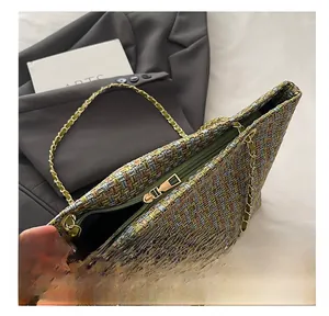Detailed view of the smooth metal zipper and textured green tweed fabric on a shoulder bag