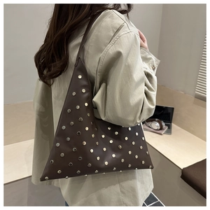 Detail of dark brown leather shoulder bag featuring silver stud rivets and a triangle shape
