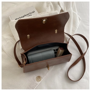 Detail of vintage brown crossbody bag interior showing storage for phone and lipstick