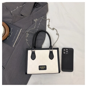 Detail of checkered texture tote bag with metal chain and fashion bags lettering