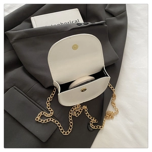 Close-up of white saddle bag interior showing gold chain strap and storage for cosmetics