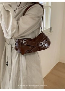 Detail of dark brown glossy leather shoulder bag with metallic buckle and bear charm