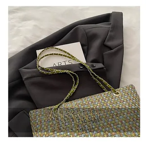 Close-up of multicolor tweed weave texture with gold chain and green leather strap