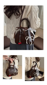 Dettaglio della borsa vintage marrone con nastri in pizzo e un ciondolo a ciliegia
