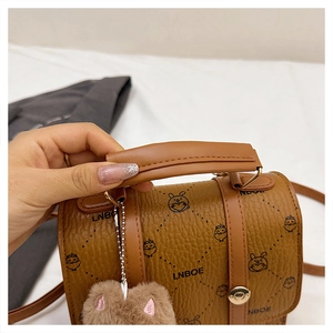 Detail of brown leather tote with cartoon prints and a heart-shaped plush charm