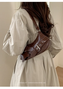 Detail of dark brown retro shoulder bag with metal buckle and bear charm on model