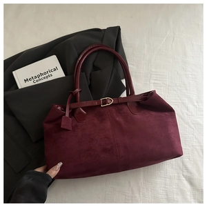 Detail of burgundy suede tote bag with round handles and strap buckle decoration