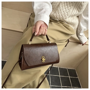 Classic dark brown leather texture handbag with gold buckle shown in a lifestyle scene