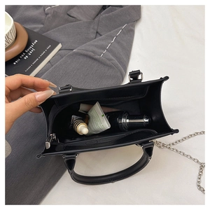Detail view of the black tote bag spacious interior with chain strap and top handle