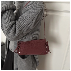 Detail of burgundy leopard print shoulder bag with bow accents and silver stud trim