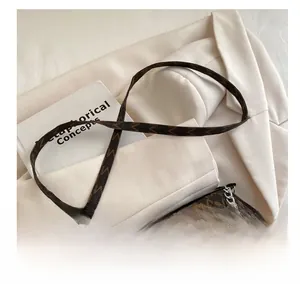Close-up of brown monogram crossbody bag with silver chain and stylish shoulder strap