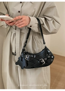 Close-up of black patent leather half-moon shoulder bag with bunny charm and silver buckle