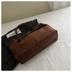 Detailed view of brown suede tote bag with leather handles on a minimalist background