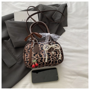 Dettaglio della borsa leopardata con fiocco in pizzo, pendente a ciliegia e perle chic