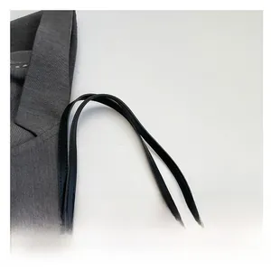 Close-up of black leather shoulder straps on a beige quilted tote bag detail