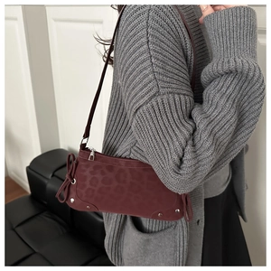 Detail of burgundy leopard print shoulder bag with bow and silver rivets on suede fabric