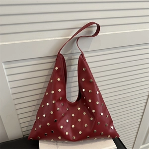 Deep red leather shoulder bag with gold rivets and triangle silhouette on a white background