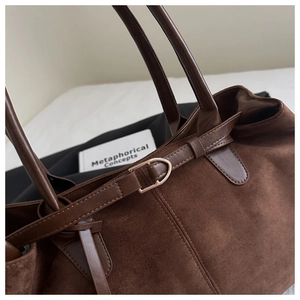 Close-up of vintage brown suede tote bag with leather straps and gold metal buckles