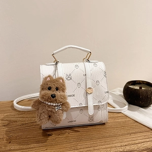 White vintage quilted backpack with cartoon print and brown plush dog charm on wood surface