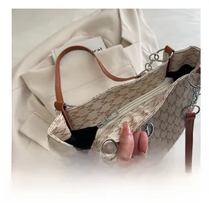 Macro detail of the smooth metal zipper and brown leather straps on the monogram tote bag