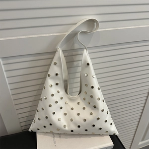 White triangle hobo bag with gold metal studs and integrated shoulder strap on books