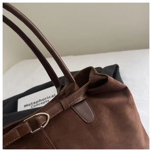 Macro detail of dark brown suede tote bag with smooth leather trim and metal buckle