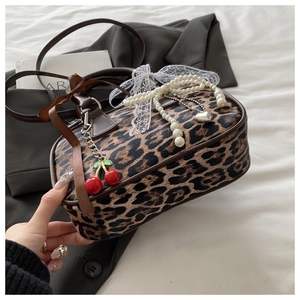 Dettaglio borsa Boston leopardata con fiocco in pizzo bianco, perle e ciondoli a ciliegia