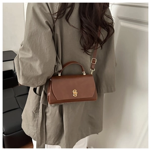 Detail view of a vintage brown leather crossbody bag with a gold metal twist lock and strap