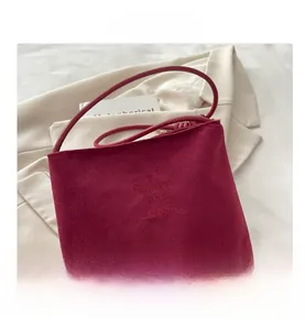 Detail of red suede tote bag showing embossed fashion and classic text on soft fabric