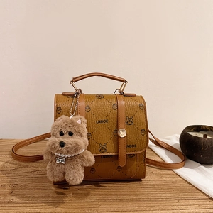 Vintage brown leather backpack with cartoon print and plush charm on wooden table