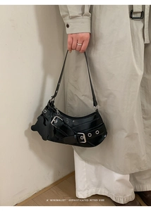 Detail of retro black crescent shoulder bag with metallic eyelets and puppy charm
