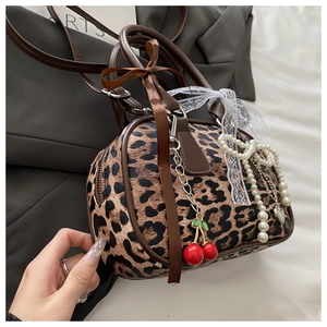 Dettaglio della borsa Boston leopardata con pizzo bianco e ciondoli a ciliegia